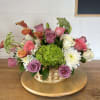 Mixed bouquet in a wicker basket with roses, calla lilies, and white daisies