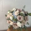 Handheld bouquet of blush roses, white blooms, and blue flowers