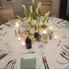 Tall white calla lilies soar above a lush base of white roses