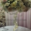 A tall, luminous centerpiece built from cream, ivory, and blush roses makes