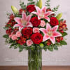 Tall bouquet of red roses and pink lilies in a clear glass vase