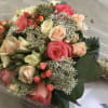 A lush cluster of blush pink, peach, cream, and deeper pink roses