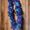 Purple and blue flower lei hanging against a wooden wall