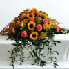 Bright yellow sunflowers paired with coral-pink carnations make a warm, uplifting sympathy