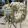 White floral wreath on an easel with a ribbon reading 
