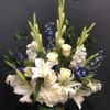 White lilies, cream roses, and blue flowers arranged in a vase