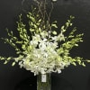 White orchid arrangement in a clear glass vase with arching green buds