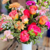 Mixed bouquet of pink and peach flowers in a white vase