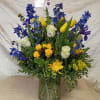 Tall blue delphinium spikes rise above sunny yellow tulips and creamy white