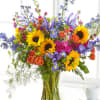 Joyful and colorful, this bouquet includes delphinium, sunflowers, iris, stock, spray roses