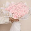 Bouquet of pale pink roses wrapped in white paper with gold trim