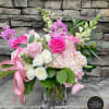 Pink and white roses, hydrangeas, and snapdragons in a clear glass cube vase with a pink ribbon.
