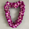 Heart-shaped purple orchid lei hanging on a wall