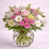 Pink roses and daisies arranged in a round glass vase