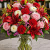 A striking luxury floral arrangement featuring blush pink roses, dramatic crimson lilies