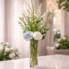A graceful and elevated arrangement featuring soft white blooms, delicate seasonal florals