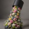 Cascade bouquet of pink, white, yellow, and blue flowers in a black hatbox