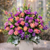 A rich and vibrant garden-style arrangement featuring premium lavender and peach roses