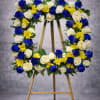 A vibrant standing wreath designed with deep blue roses, white roses, yellow
