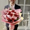 Man holding a large bouquet of red and pink roses wrapped in pink paper
