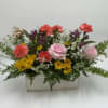 This cheerful arrangement features soft pink roses, coral carnations, sunny yellow daisies