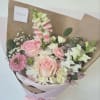 Hand-tied bouquet of pink and white flowers wrapped in brown paper