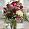 Red roses and pink lilies arranged in a clear glass vase