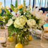 Bright clusters of white hydrangeas and roses anchored in a clear glass