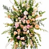 Soft pink roses, creamy lilies, peach snapdragons and white carnations form a