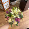 Handheld bouquet of white lilies, pink roses, and purple flowers