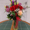 Mixed bouquet of red roses, lilies, and purple flowers in a glass vase