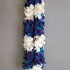 A long floral lei made of white and blue-purple blossoms.