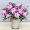 Pink peonies arranged in a white vase with airy greenery