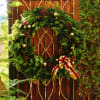 Evergreen wreath with pinecones and a red-and-gold bow on a wooden gate