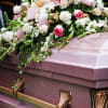 Pink and white floral casket spray on a mauve casket