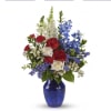 Red and white roses with blue flowers in a cobalt vase
