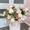Pink and white roses arranged in a round hatbox