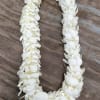White flower lei laid in a U shape on a wooden surface