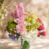 A soft and romantic garden-inspired arrangement featuring blush roses, green cymbidium orchids