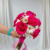 Handheld bouquet of hot pink roses and white daisies with a pink ribbon