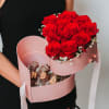 Woman holding a pink heart-shaped box with red roses and chocolate-covered strawberries