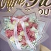 Rounded hand-tied bouquet of pink and white roses with delicate fillers, layered
