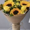 Bouquet of yellow sunflowers and roses wrapped in brown paper