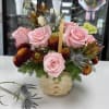 Pale pink roses and mixed blooms in a rustic wicker basket with