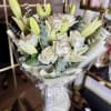 A refined arrangement of creamy white roses and elegant lilies, accented with