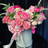 Pink and white roses arranged in a round hatbox with ribbon and pearl accents
