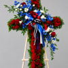 A large, formal cross of dense red blooms set against bright blue
