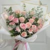 A dense cluster of  pink roses forms a rounded hand-tied bouquet