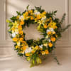 A radiant ring of sunny yellow roses and pale lilies greets the