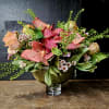 Pink speckled orchids and peach roses in a glass vase